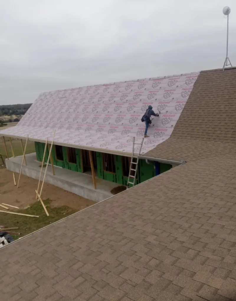 Worker preparing underlayment for a metal roof installation in Minnetrista